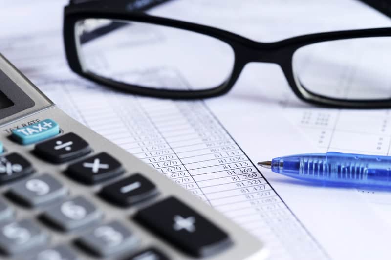 glasses and calculator sitting on top of spreadsheets